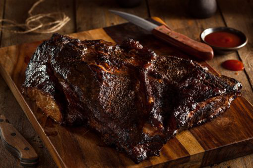 BBQ Brisket on a wood cutting board with a steak knife