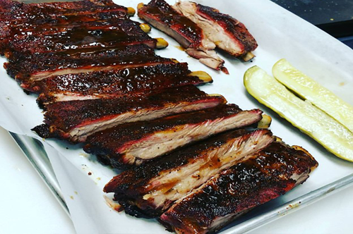 pan of BBQ ribs with two pickles
